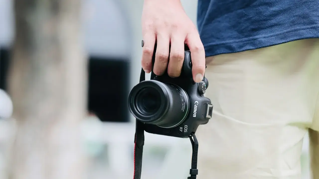 Dłoń trzyma aparat Canon EOS R7, gotowy do uchwycenia chwili. Jego matryca w aparacie zapewni doskonałą jakość zdjęć.
