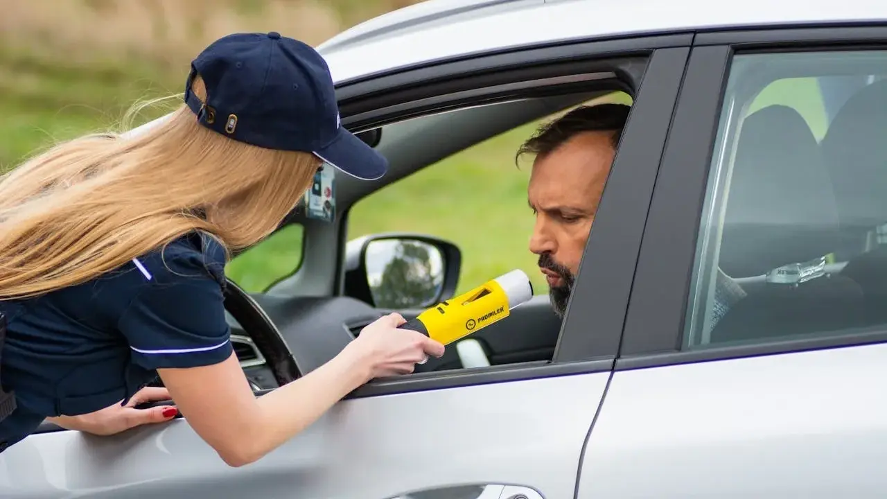 Policjantka mierzy kierowcy alkomatem, sprawdzając, czy nie przekroczył dopuszczalnego limitu promili.