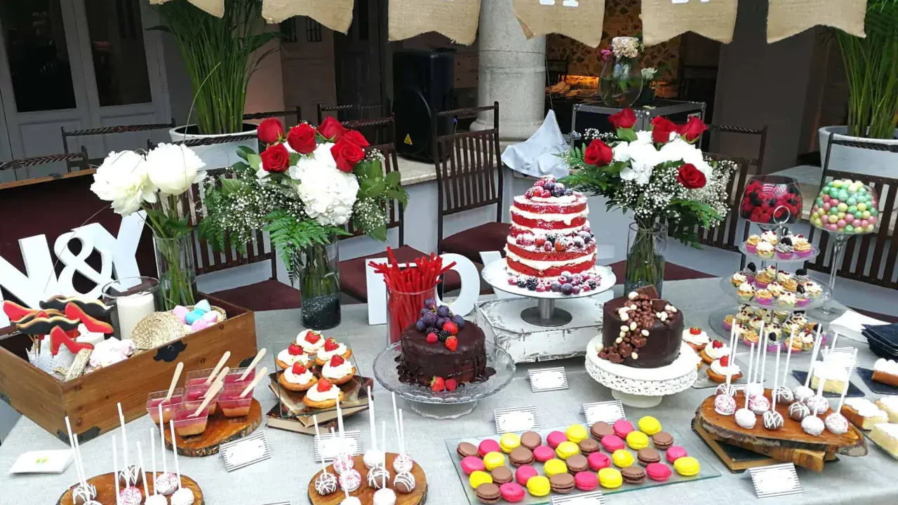 Una encantadora mesa dulce boda con pasteles, cupcakes, macarons y flores.