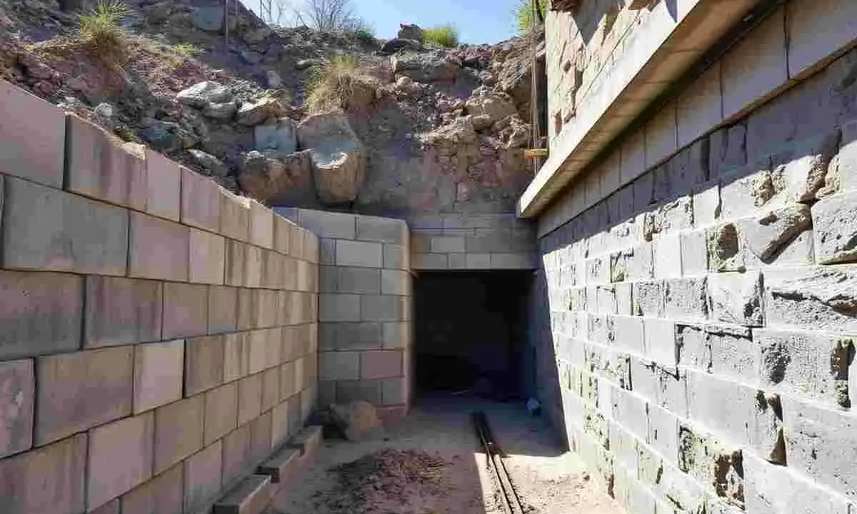 Bauarbeiten an einem Tunnel, der nach DIN 18532 errichtet wird. Mauern aus Betonsteinen und ein Eingang in den dunklen Tunnel.