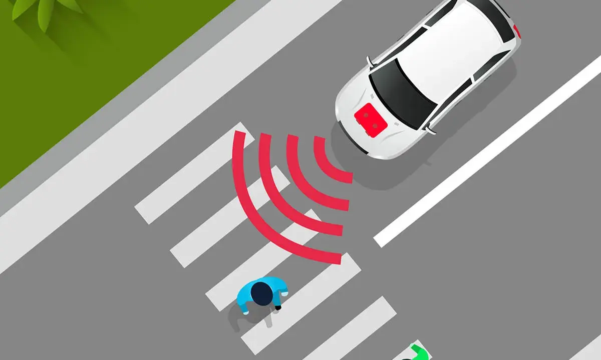 Coche eléctrico blanco se acerca a un paso de peatones. El sonido de los coches eléctricos es casi inaudible, pero las ondas rojas indican que detecta a los peatones.