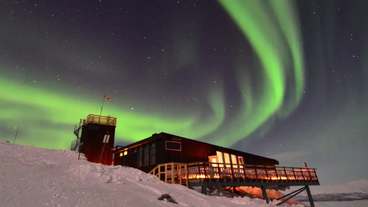 Abisko Sky Station badar i norrskenets gröna ljus. En magisk natt i svenska Lappland.