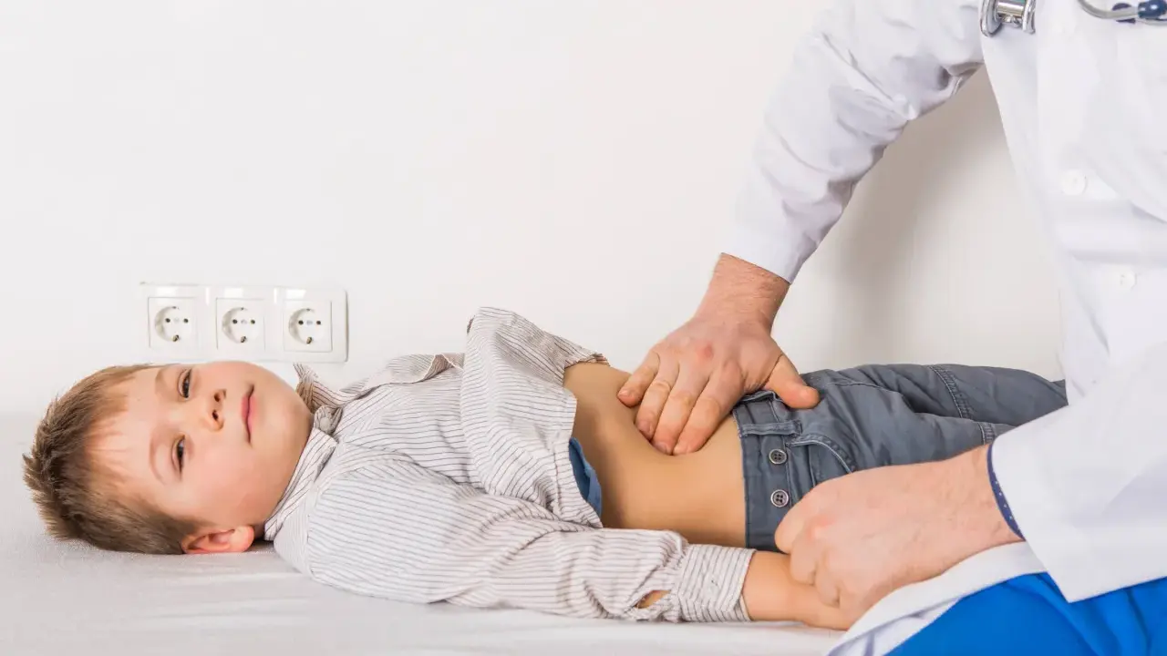 Médico examina el abdomen de un niño con posible gastroenteritis.