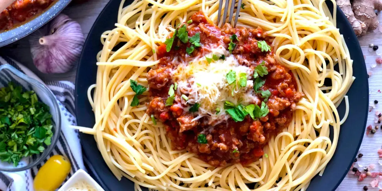 Spaghetti bolognese, prosty przepis. Aromatyczny sos mięsny z mielonym mięsem i pomidorami na złocistym makaronie, posypany serem i natką pietruszki.