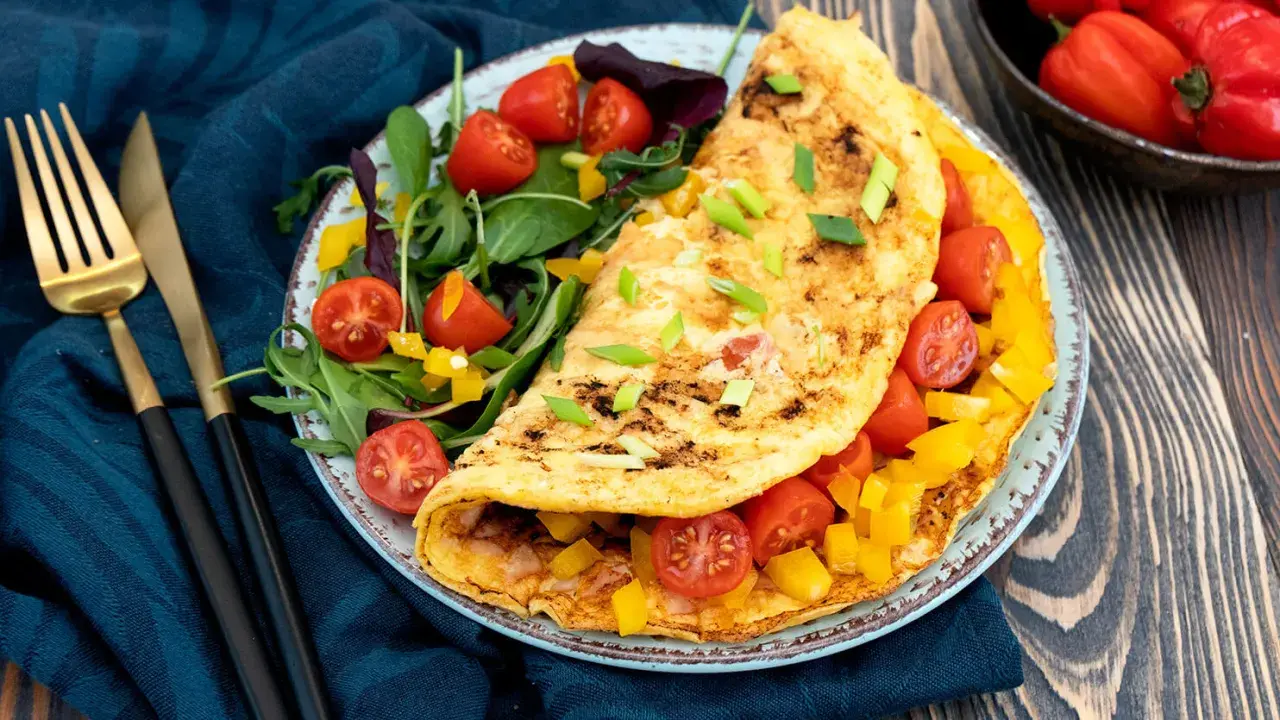 Pyszny omlet fit z pomidorkami i papryką, podany z sałatką. Idealny na zdrowe śniadanie.