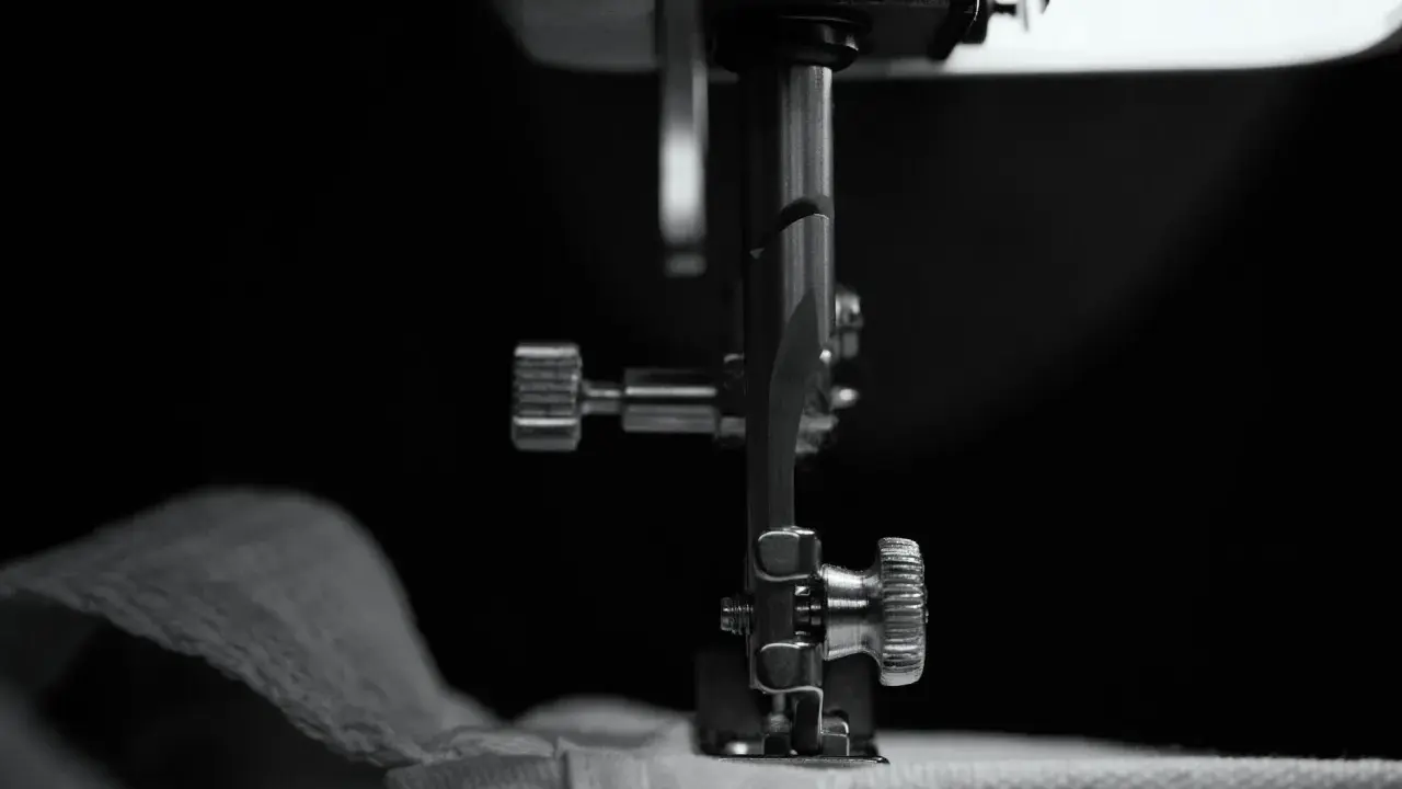 Zbliżenie na stopkę maszyny do szycia, która przygotowuje się do pracy nad puszystymi wzorami na drutach.