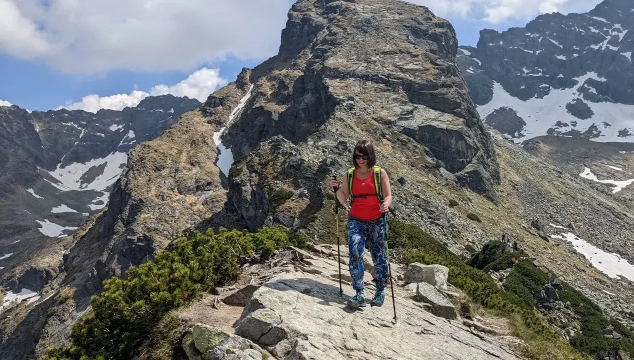 Kobieta z kijkami trekkingowymi na szlaku w Dolinie Gąsienicowej, pod majestatycznym szczytem.