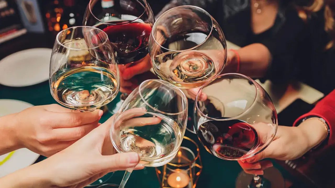 Ludzie wznoszą toasty winem. Pamiętaj o odpowiedzialnym spożywaniu alkoholu, zwłaszcza gdy rozważasz antykoncepcję.