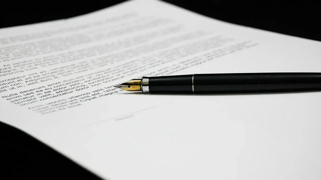 Una penna stilografica nera su un foglio di testo, forse una lettera di richiamo per assenza ingiustificata.