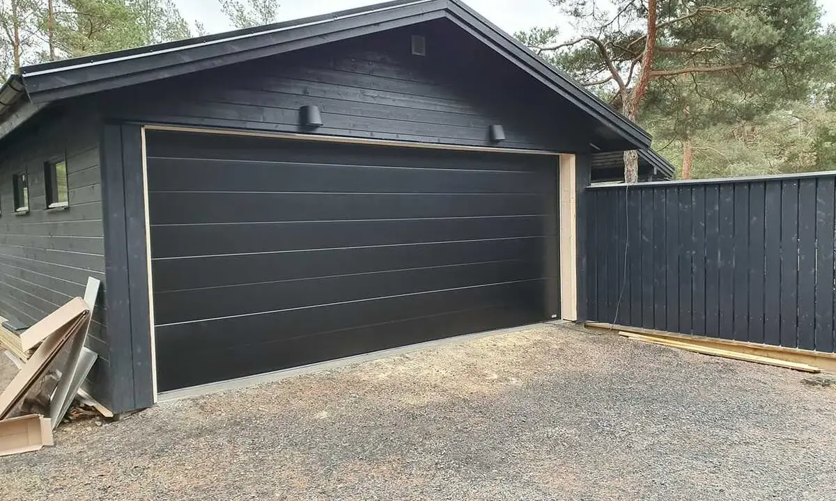 Nyinstallerad svart garageport montering på ett mörkt garage.