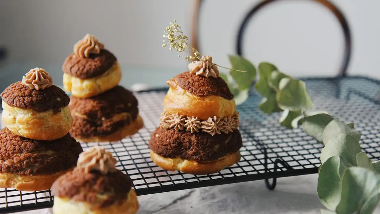 Délicieuses religieuses au chocolat, empilées sur une grille, ornées de crème et d'une touche de verdure.