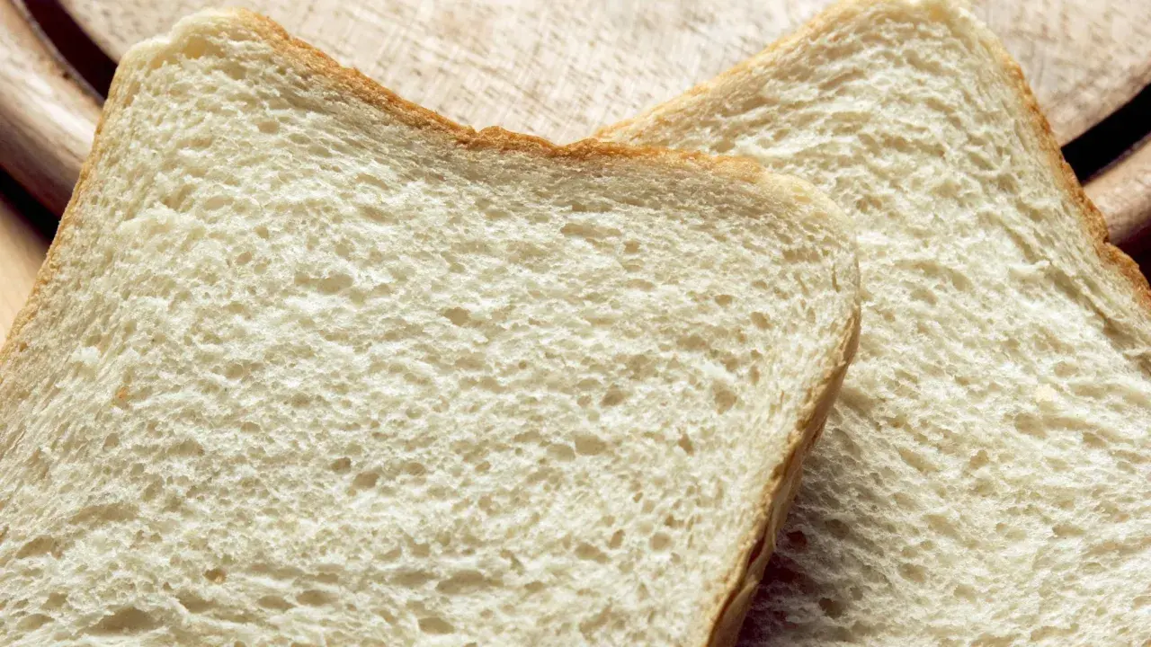 Zwei Scheiben Weißbrot liegen auf einem Holzbrett. Die Frage "wie viel Kalorien hat eine Scheibe Toast?" beschäftigt viele.