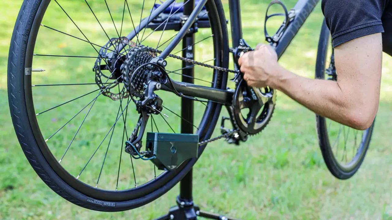 Rowerzysta zakłada łańcuch w rowerze z przerzutkami. Pokazano tylną przerzutkę, kasetę i korbę.