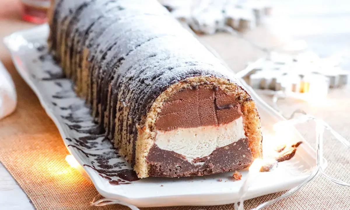 Bûche glacée chocolat, vanille et chocolat, saupoudrée de sucre glace. Une délicieuse recette pour les fêtes.