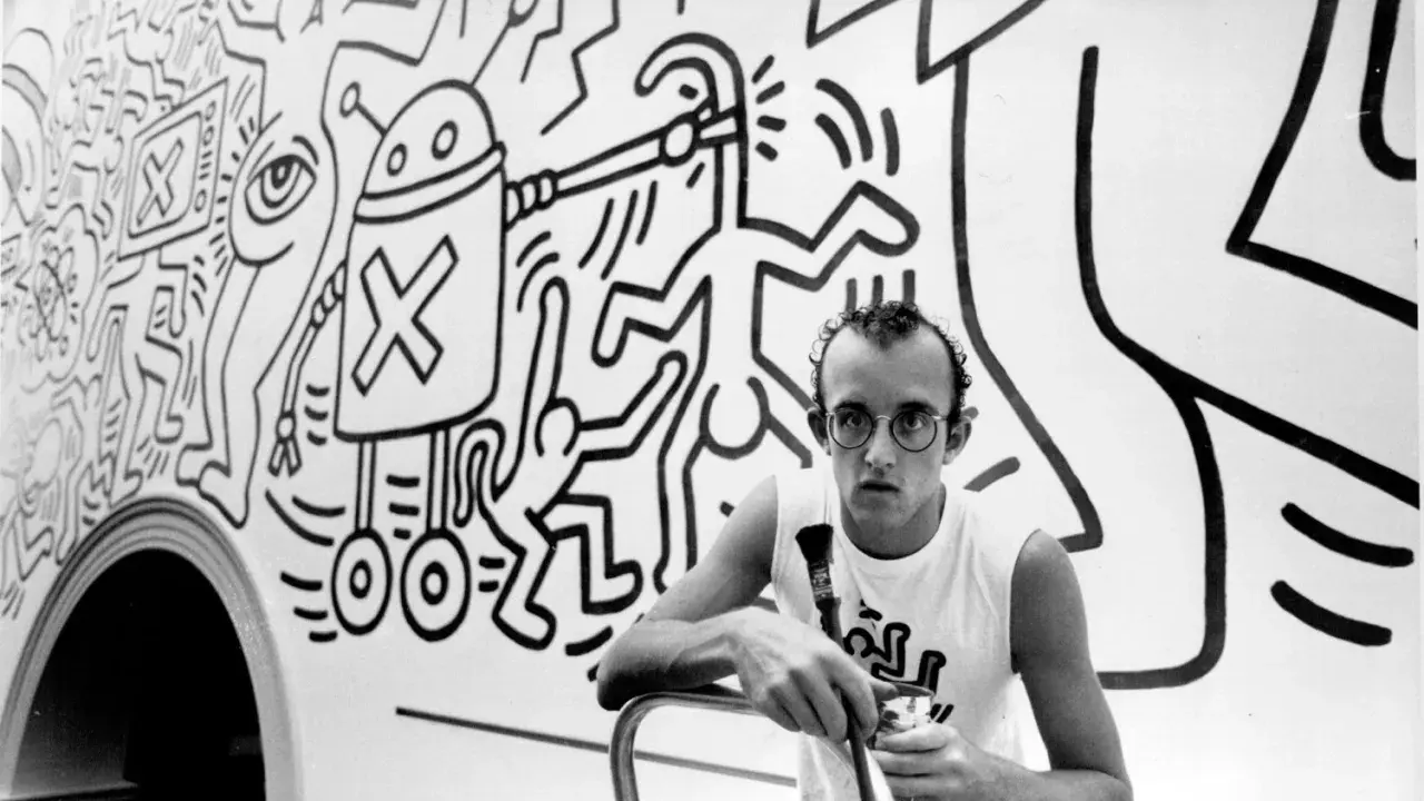 Keith Haring, a pioneer of queer art, poses with his iconic figures in this black and white image.