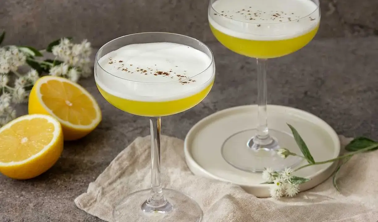 Två eleganta glas med en gul Galliano drink, toppad med vitt skum och strödd kanel. Citroner och blommor ger en fräsch touch.