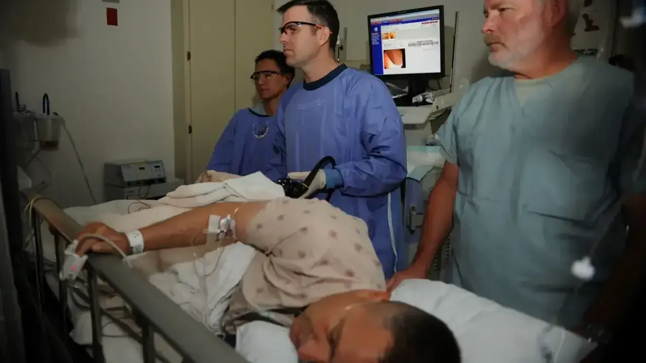 Lekarze przeprowadzają badanie, które wyjaśnia, co to jest kolonoskopia. Pacjent leży na łóżku, a lekarz wykonuje zabieg.