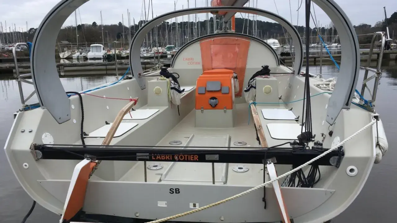 Le voilier "L'Abri Cotier" SB, un modèle kaidoz 31, est amarré dans un port. Son design moderne avec une arche distinctive est visible.
