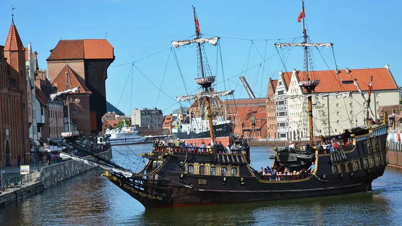 Gdański galeon "Lew" z pasażerami na pokładzie, na tle zabytkowej architektury miasta. To jeden z 7 ciekawych faktów o Polsce, które można odkryć w tym mieście.