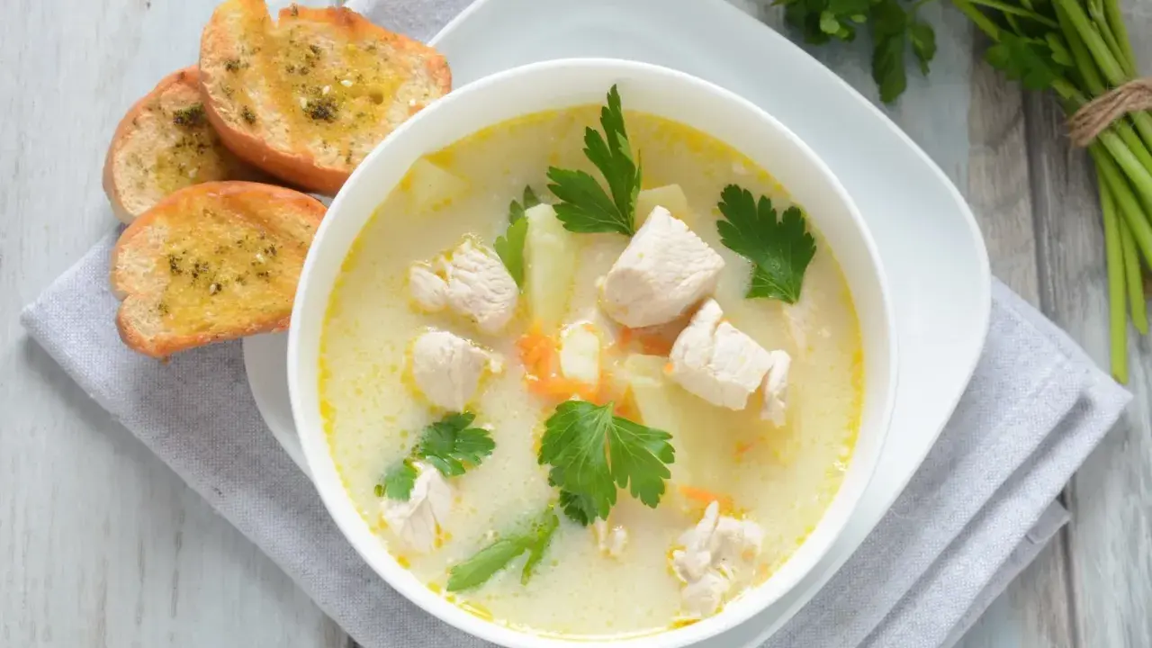 Aromatyczna zupa z kurczakiem z kawałkami mięsa, ziemniaków i marchewki, podana z grzankami czosnkowymi.
