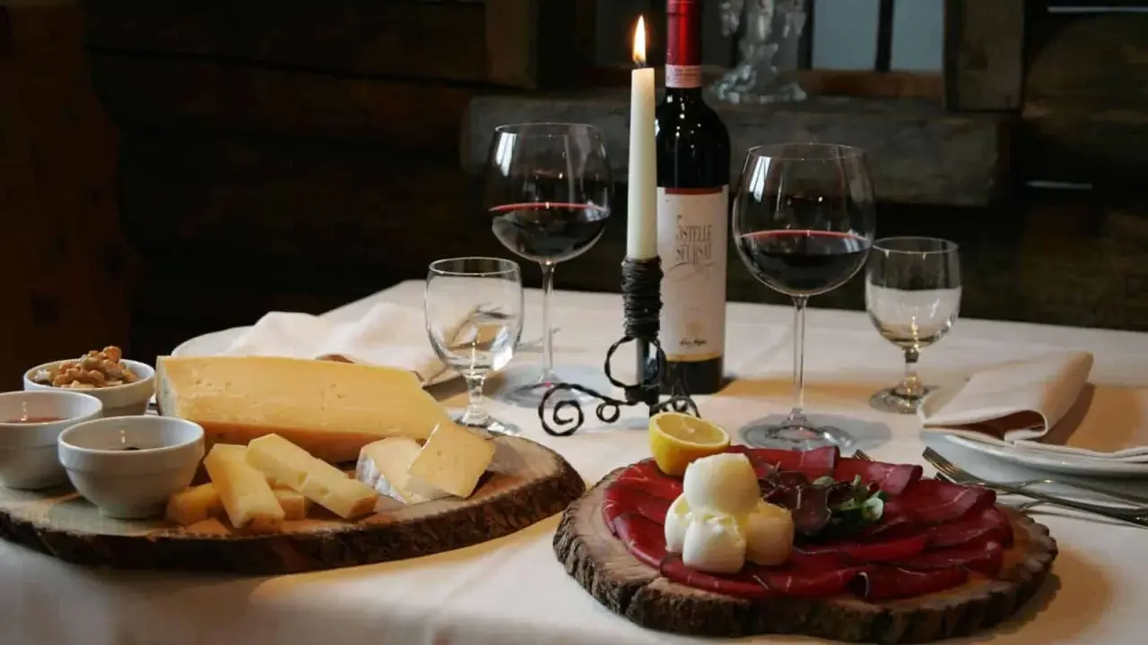 Tagliere con formaggi e bresaola, accompagnati da vino rosso e candela. Un assaggio dei piatti tipici Valtellina.