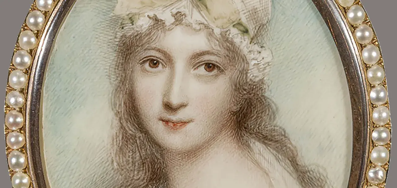 A delicate miniature portrait of a woman in a bonnet, framed by pearls. This tiny artwork captures a moment in time, showcasing the artistry of miniature portraits.