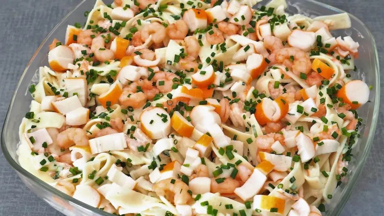 Salade Marco Polo : pâtes, crevettes, bâtonnets de surimi et ciboulette dans un plat en verre.