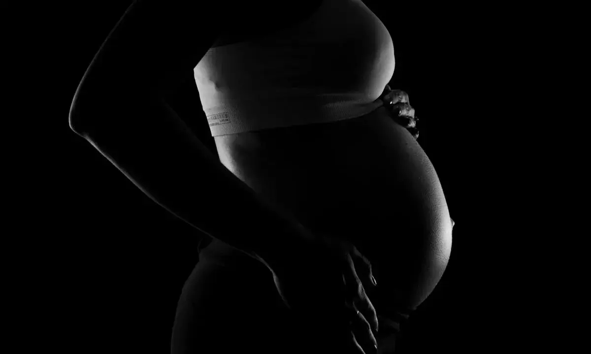 Silhuett av en gravid kvinna som håller sin mage. Bilden kan associeras med vena cava syndrom gravid.