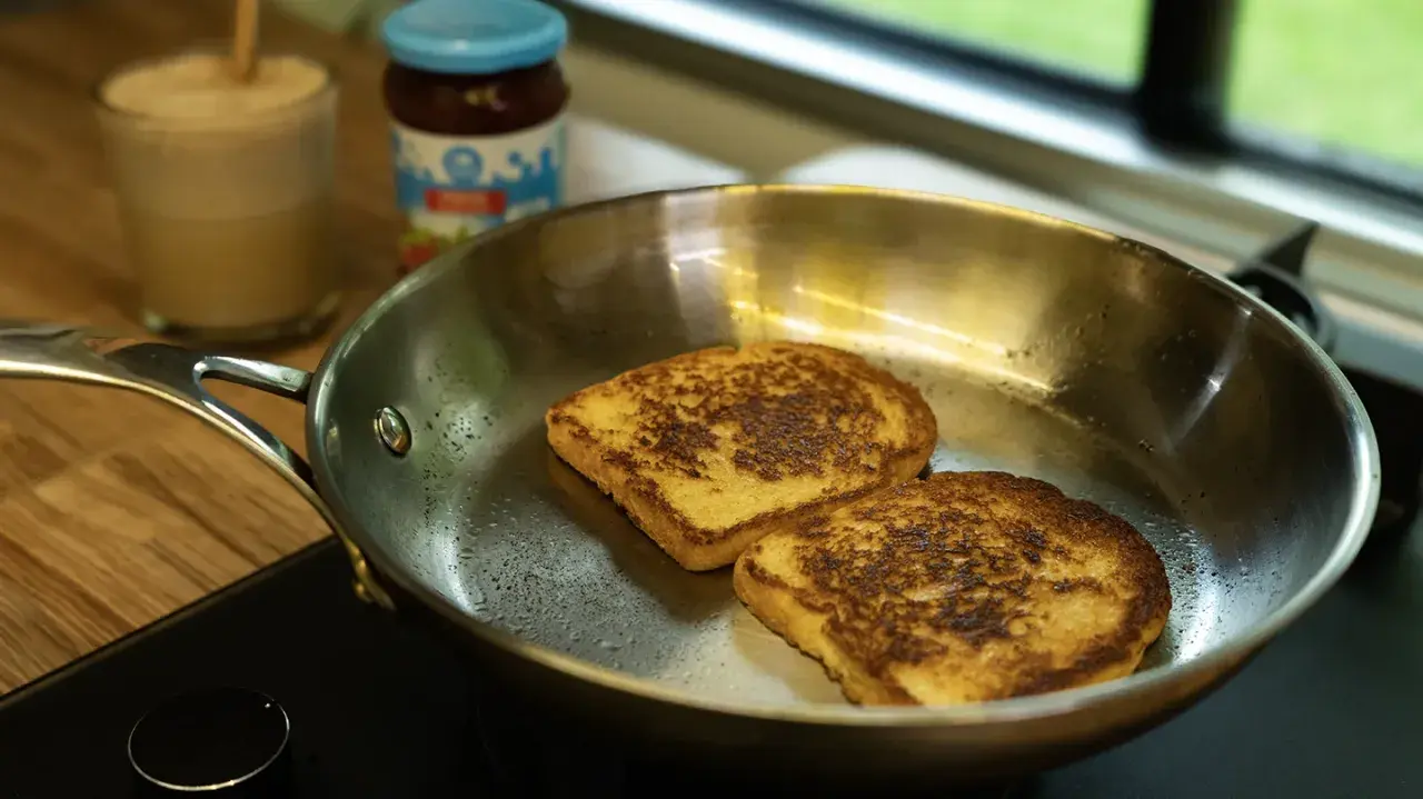 Dos tostadas francesas dorándose en una sartén de acero inoxidable, mostrando las ventajas e inconvenientes de este material para cocinar.
