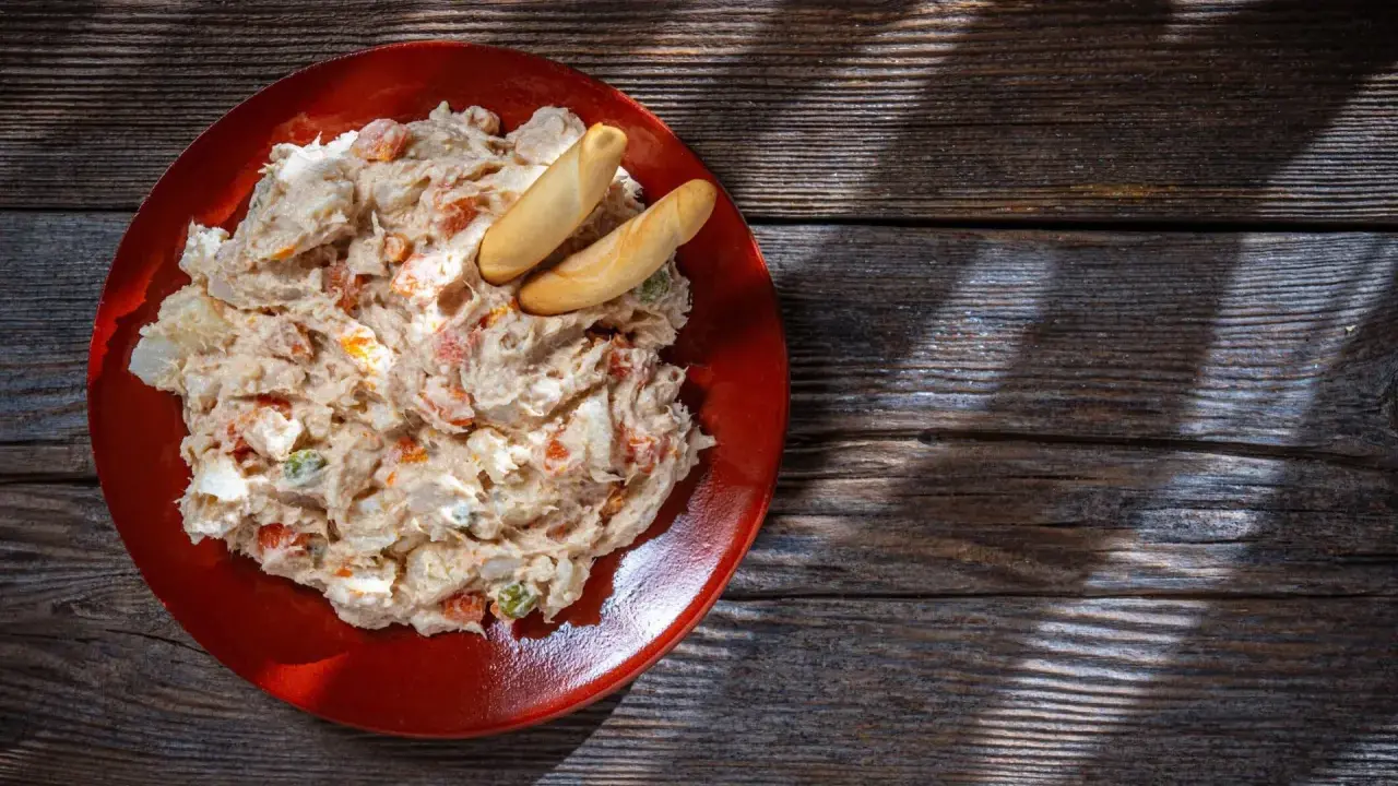 Ensaladilla rusa cremosa en plato rojo, con palitos de pan. ¿Cuanto dura la ensaladilla rusa en la nevera?