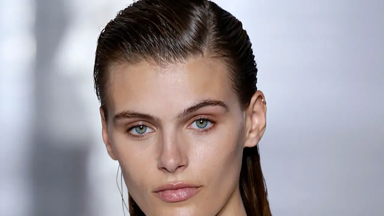 Ein Model mit glänzenden, nassen Haaren im Wet-Look-Stil, das einen intensiven Blick in die Kamera wirft.