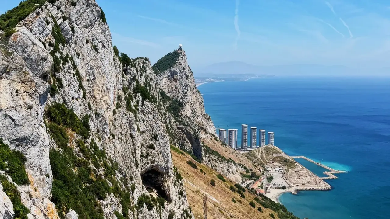 Widok na Skałę Gibraltarską z jaskinią, budynkami i morzem.