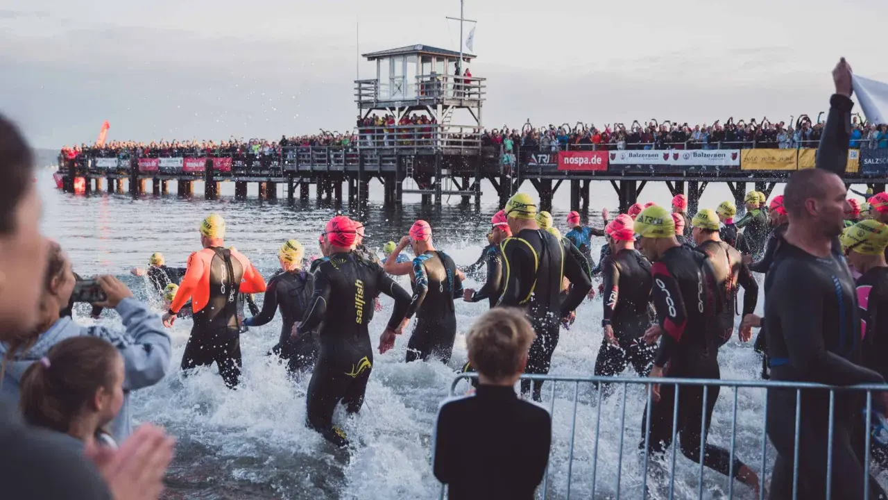 Triathleten starten ins Wasser, die Menge jubelt vom Steg. Die Ironman Vorbereitung ist in vollem Gange.