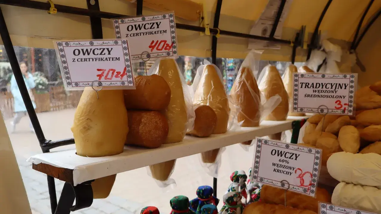 Oscypek na straganie, z metkami cenowymi i ozdobnymi figurkami.