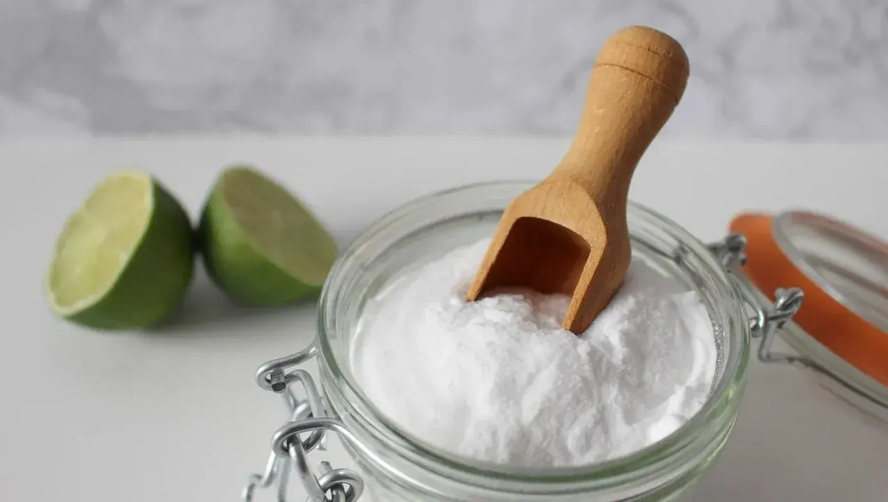 Bicarbonato e lime, ingredienti naturali per combattere la forfora. Un cucchiaino di bicarbonato in un barattolo di vetro.