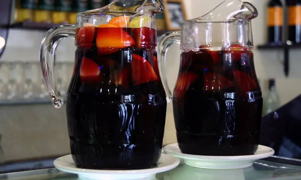 Dwa dzbanki z ciemnym napojem i owocami, idealne na lato. Przepis na tinto de verano.