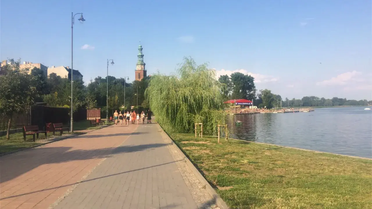 Spacer po chełmno trasa nad jeziorem. W oddali widać wieżę kościelną i zabudowania.