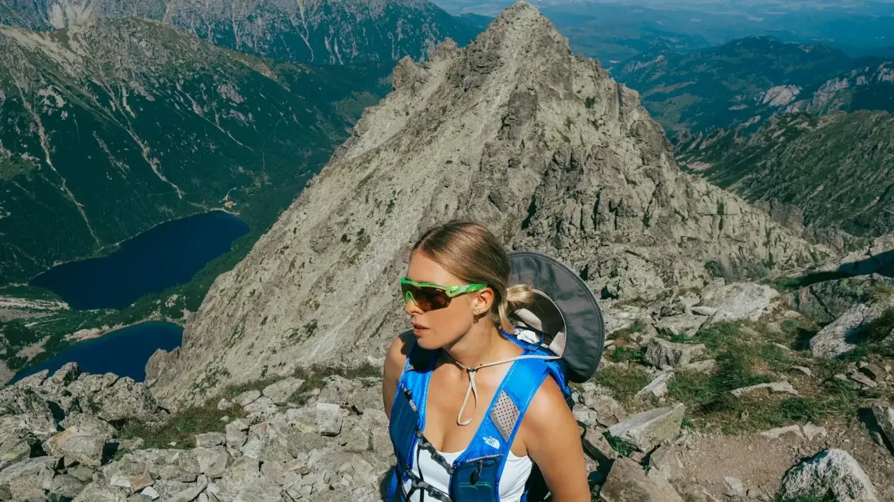 Kobieta w okularach i niebieskim plecaku na tle górskich krajobrazów. Beskid Śląski oferuje takie widoki i atrakcje.