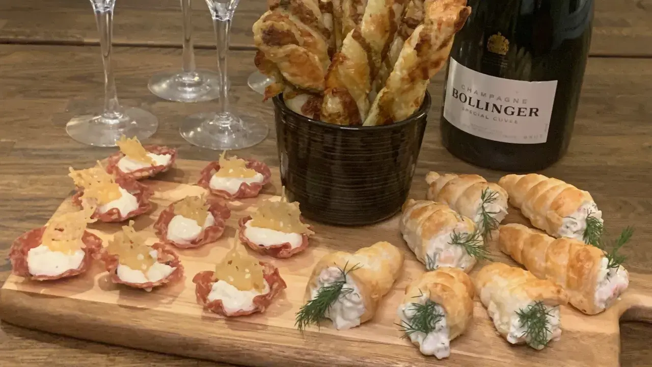 En flaska Bollinger och en bricka med läckra tilltugg till bubbel: små salta korgar, smördegsrullar och ostpinnar.