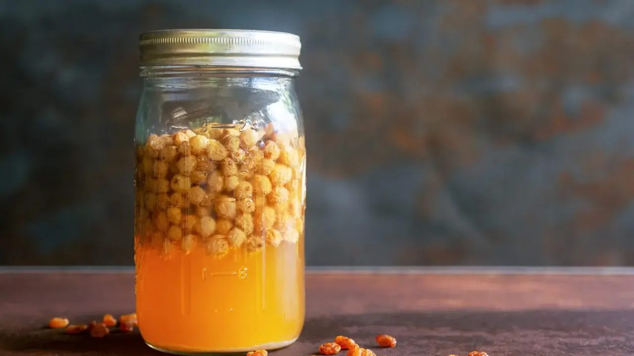 Glas mit süßem Saft und Rosinen, bereit, um Hefe selber machen zu beginnen.