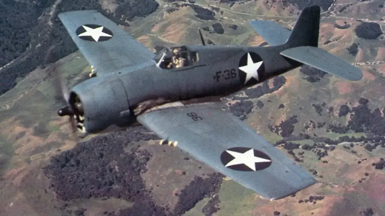 F6F Hellcat fliegt über hügelige Landschaft.