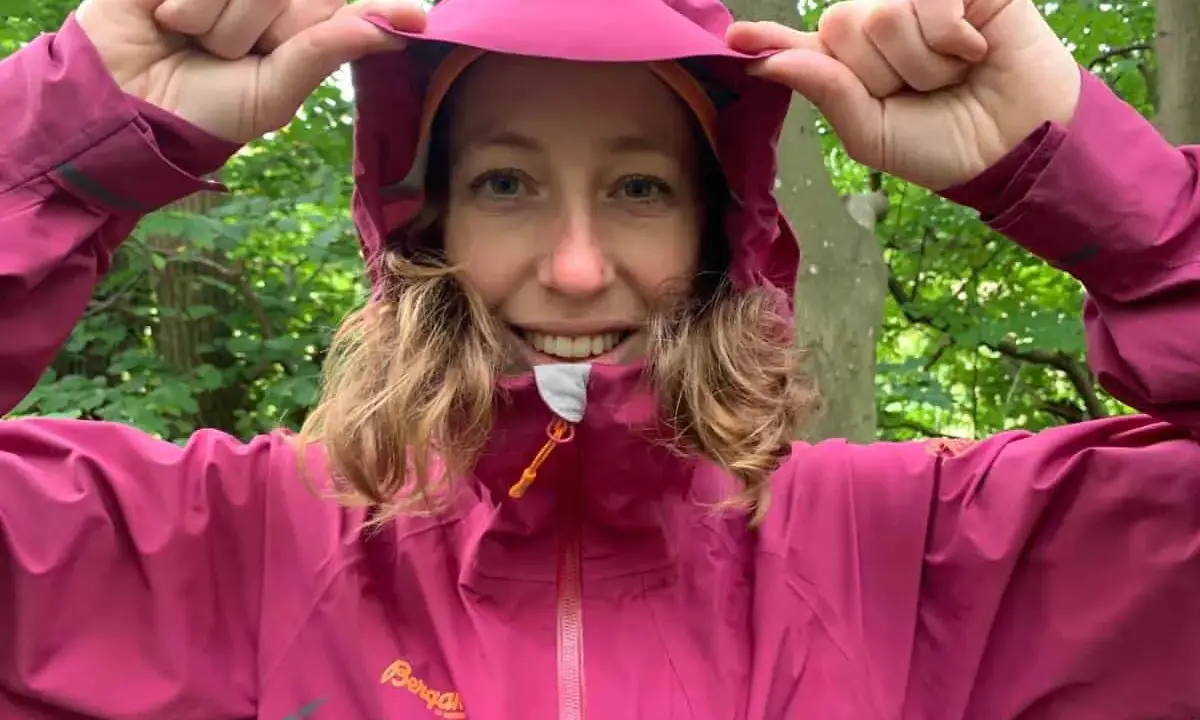 Kvinna i skogen drar upp huvan på sin rosa jacka, redo för 5000 vattenpelare.