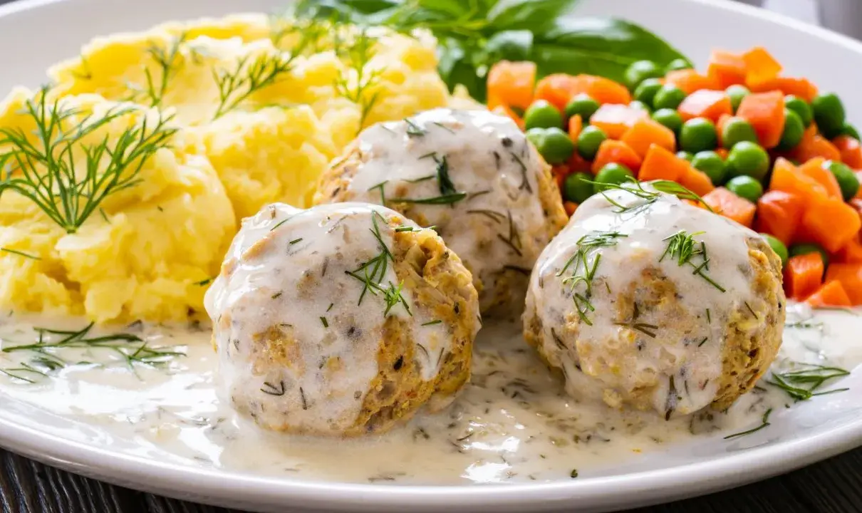 Pyszne pulpety z indyka w sosie koperkowym, podane z puree ziemniaczanym i warzywami.