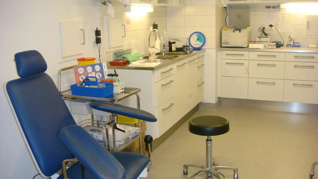 Blå undersökningsstol och medicinsk utrustning i ett kliniskt rum. Förberedelser för att testa för tyfoidfeber.