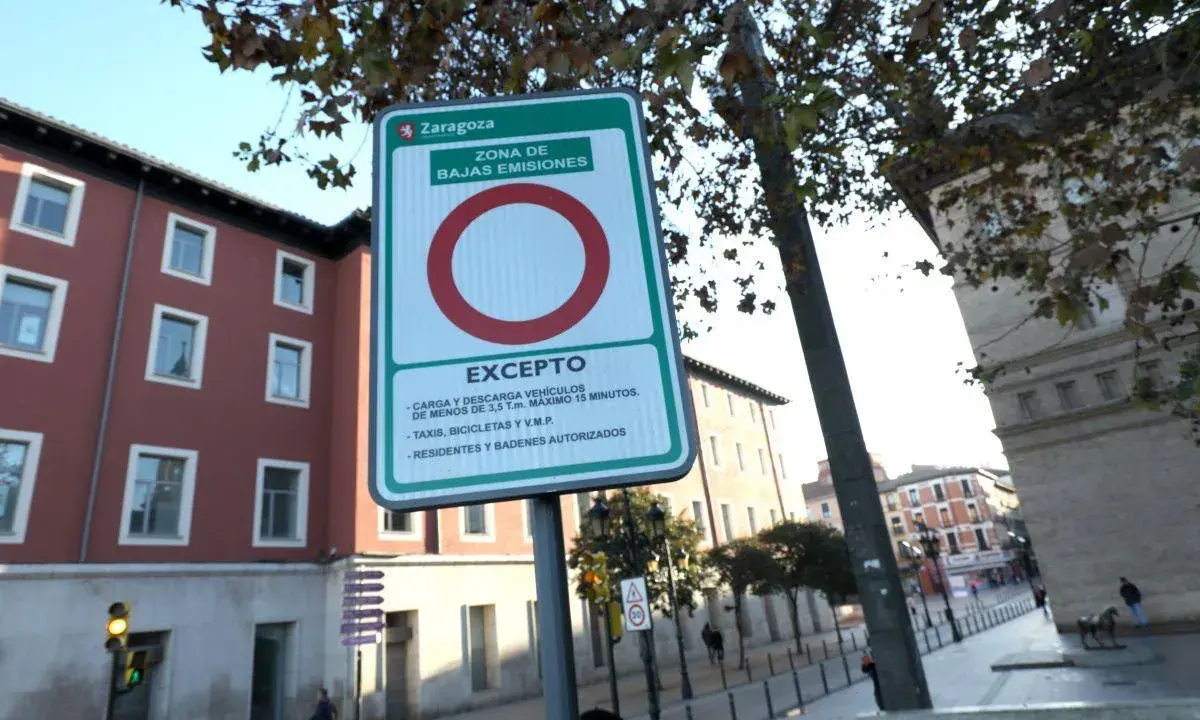 Señal de etiqueta medioambiental en Zaragoza, indicando zona de bajas emisiones con excepciones para carga, descarga, taxis, bicicletas y residentes.