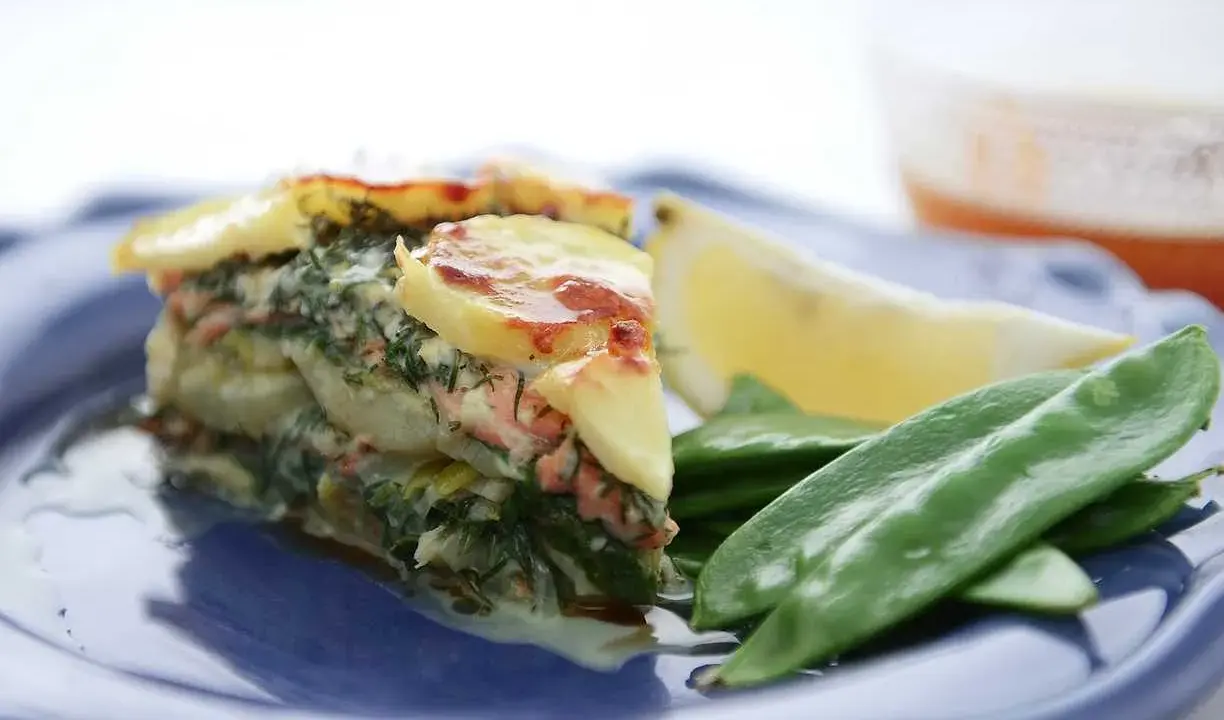Laxpudding med gravad lax, potatis och dill. Serveras med sockerärtor och citronklyfta.