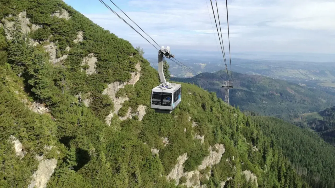 Kolejka linowa wjeżdża na zbocze porośnięte kosodrzewiną, oferując widok z Kasprowego na Giewont.