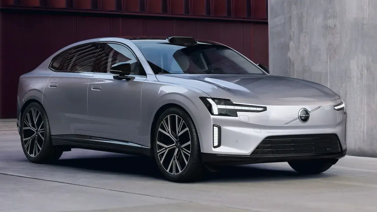 La nouvelle Volvo ES90, une berline électrique argentée aux lignes épurées, se gare devant un bâtiment moderne.