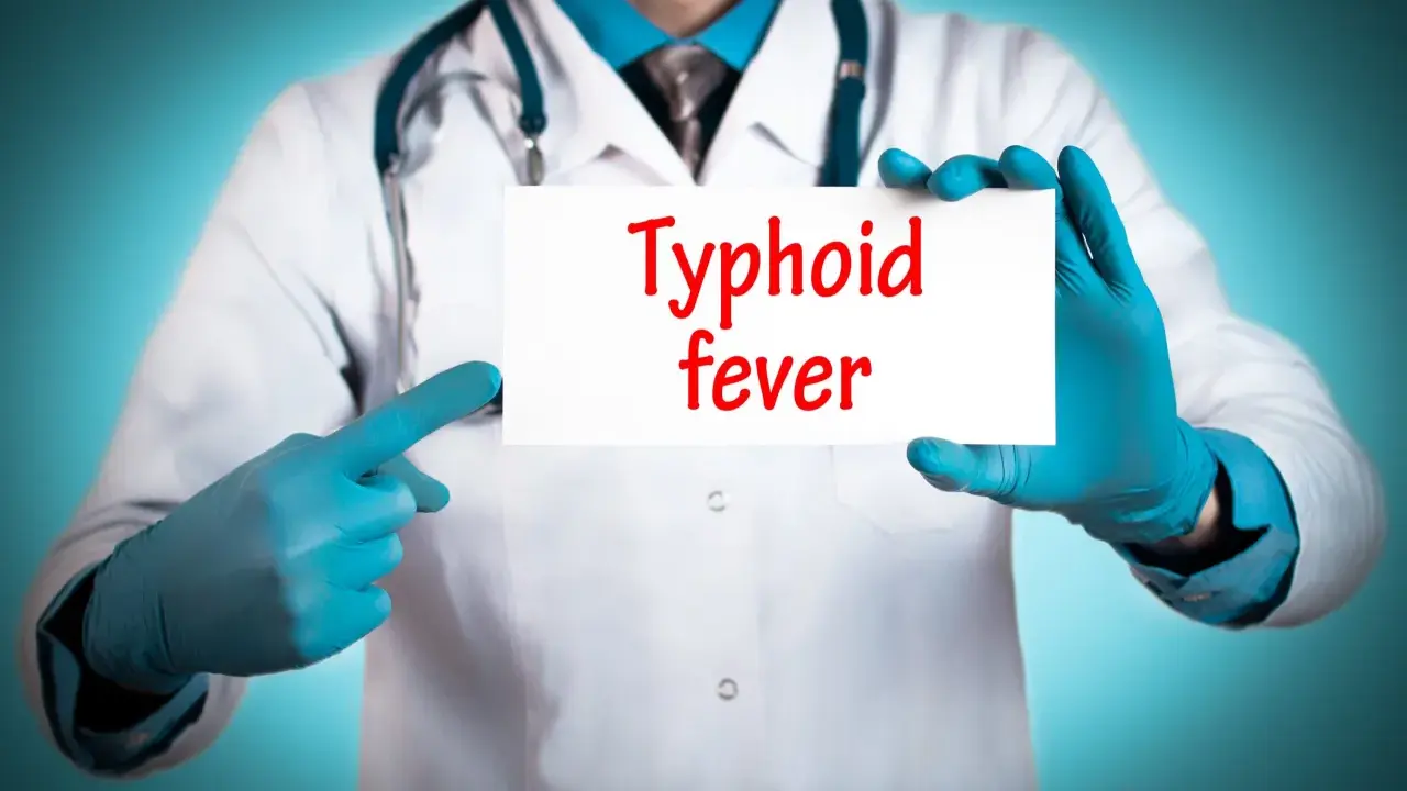 Läkare med blå handskar pekar på en skylt med texten "Typhoid fever".