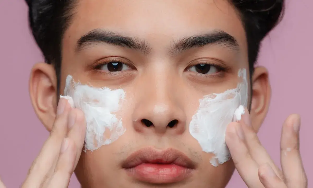 Uomo applica crema sul viso per una pelle perfetta.